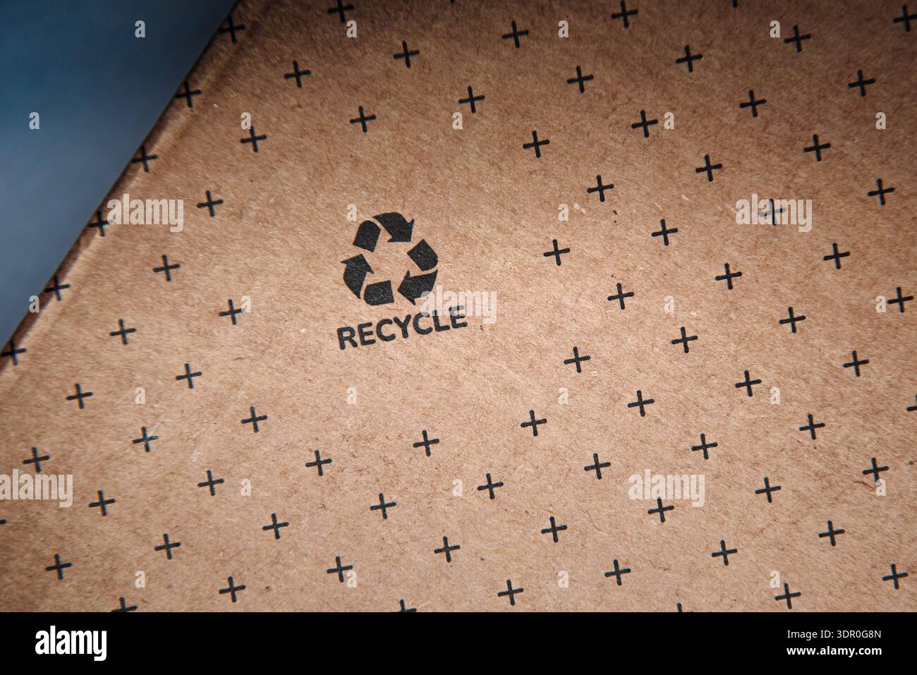 Struttura in cartone marrone con simbolo di riciclo nero e dettagli macro a motivo incrociato sfondo del materiale di imballaggio ecologico per un design sostenibile Foto Stock