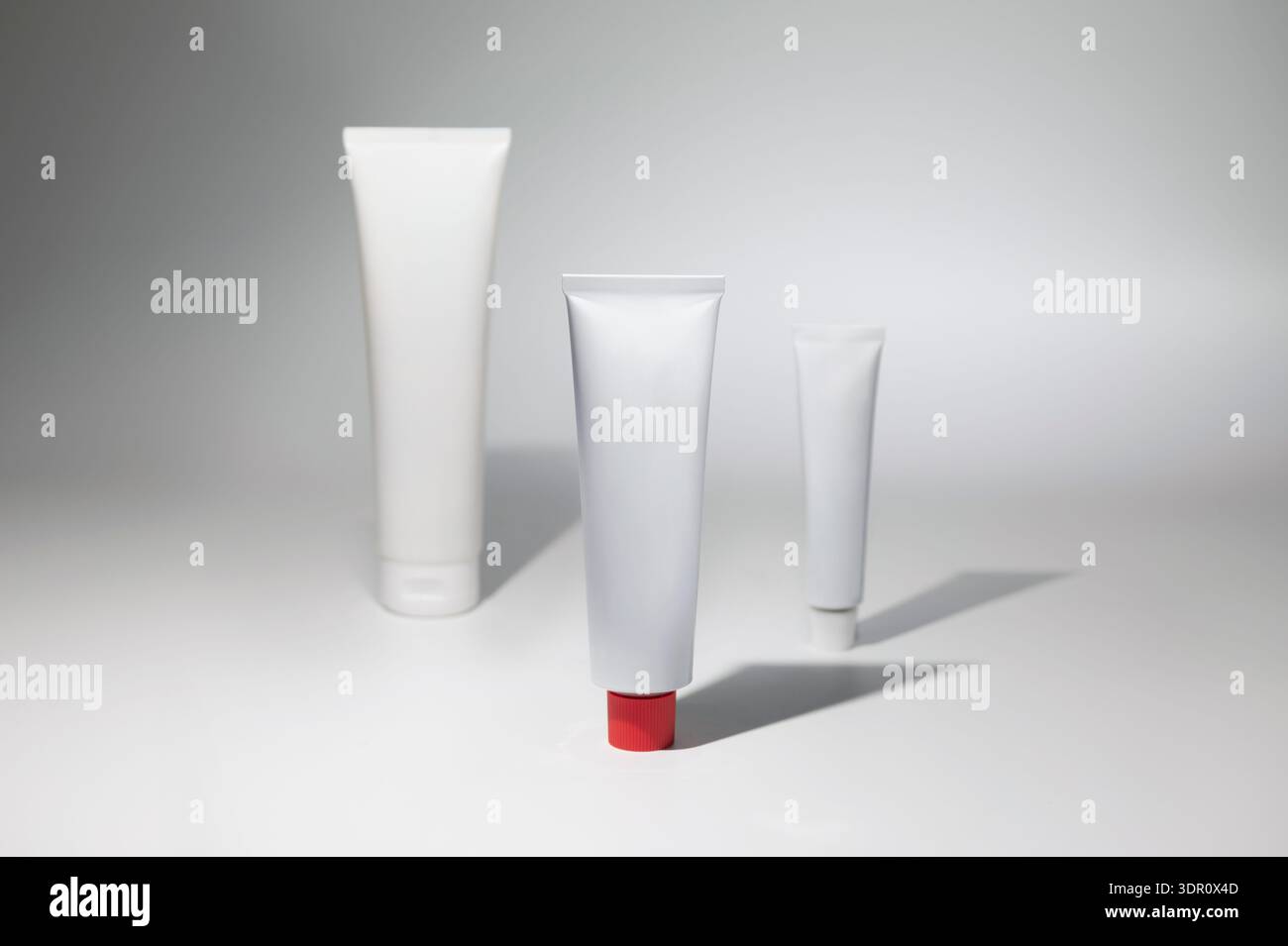 Mockup di un bianco di un tubo di crema o unguento, un prodotto paraparmacico, stazionario, altri tubi sfocati sullo sfondo Foto Stock