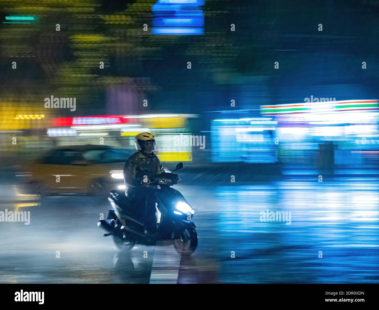 I motociclisti percorrono le strade notturne piovose della città di Taipei. Foto Stock