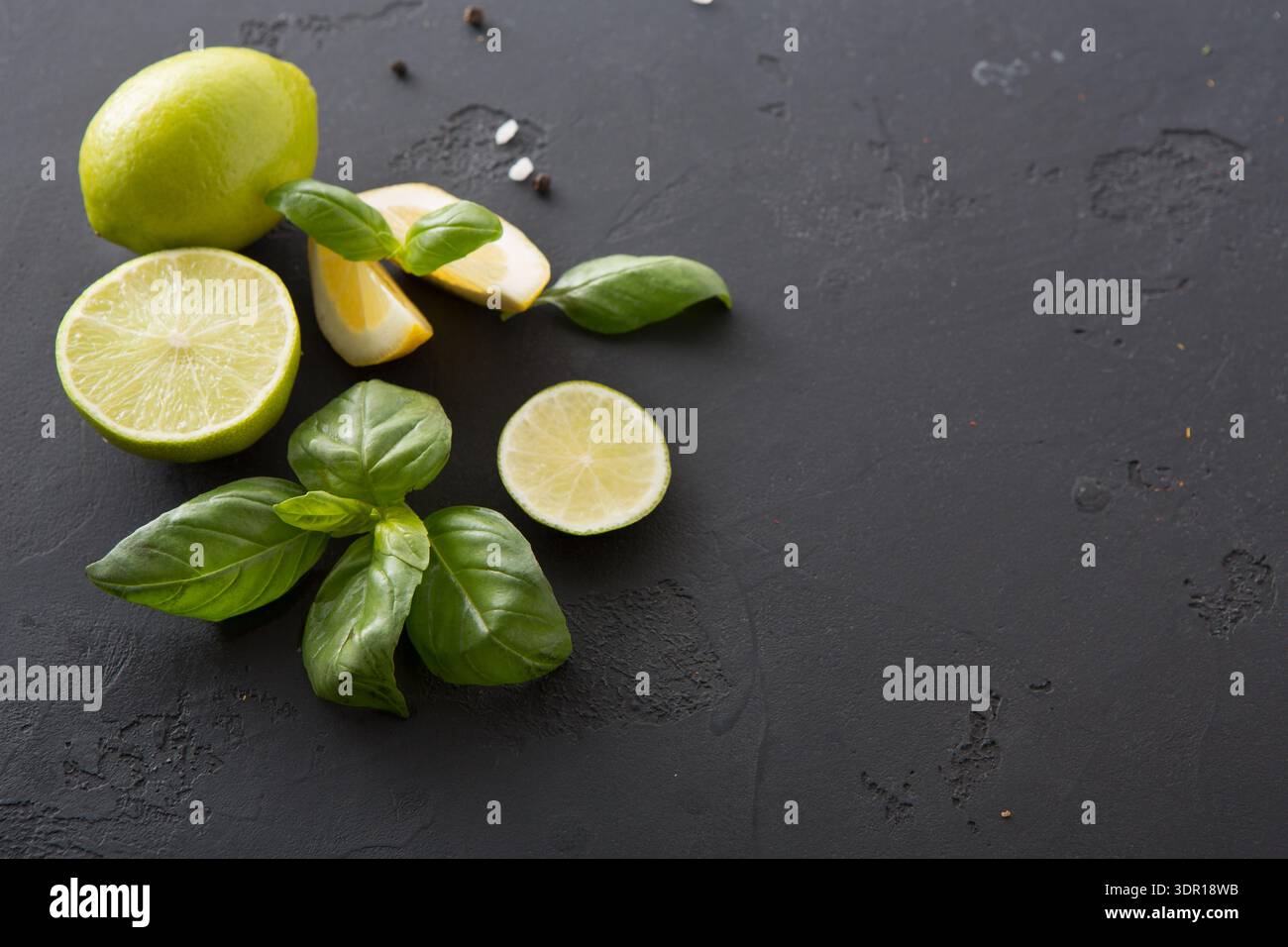 Calce fresca e basilico disposti su superficie scura con fette e foglie Foto Stock