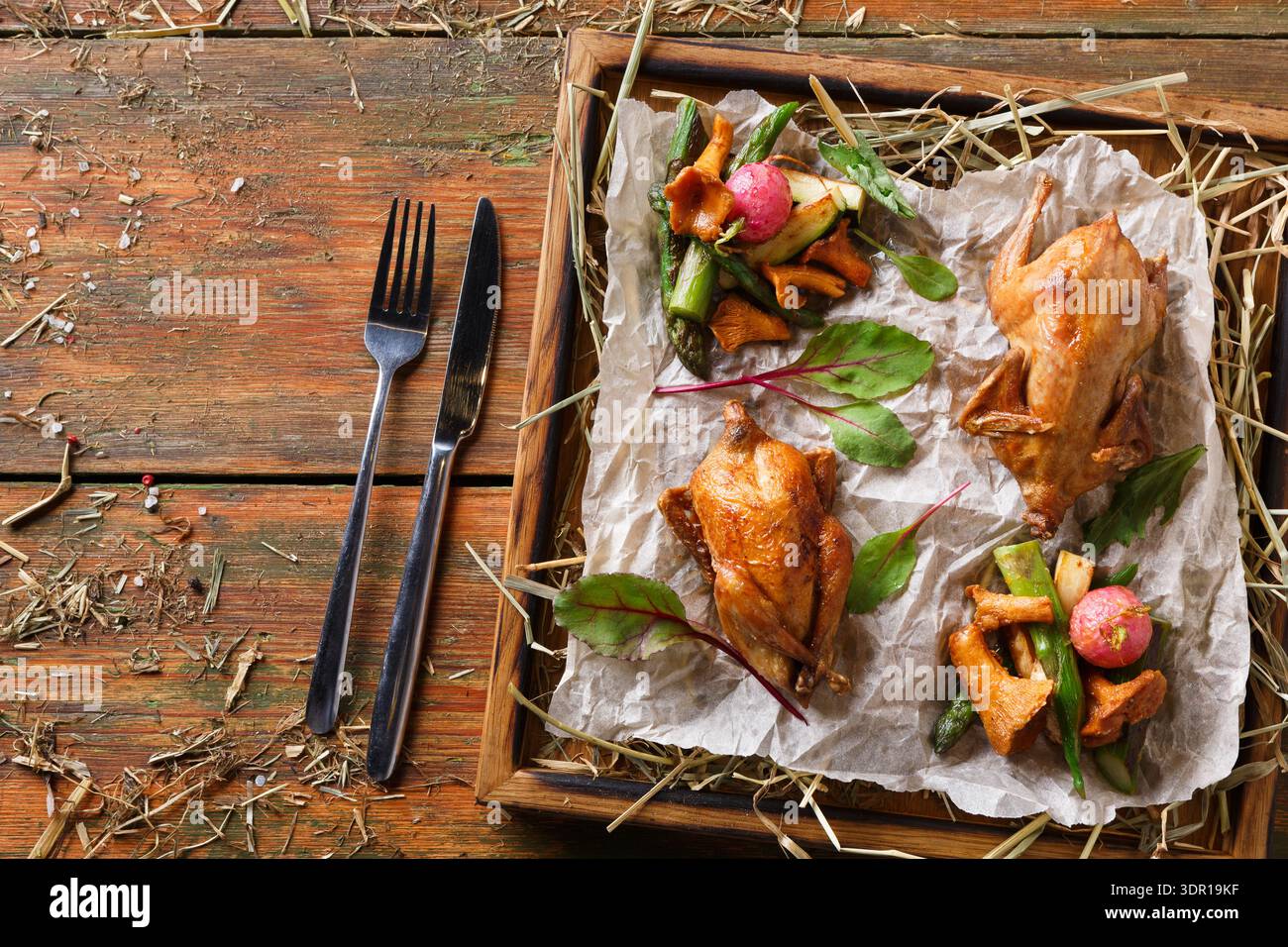 Galline di caccia deliziosamente cotte servite su un tavolo di legno con verdure fresche ed erbe aromatiche Foto Stock