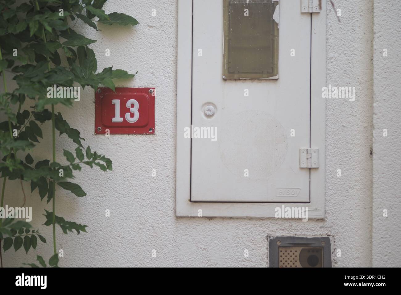 Casa numero 13 con una cassetta postale su un muro bianco Foto Stock