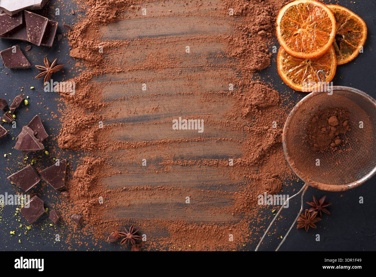 Polvere di cioccolato e cacao con arance affettate su una superficie scura in un ambiente da cucina Foto Stock