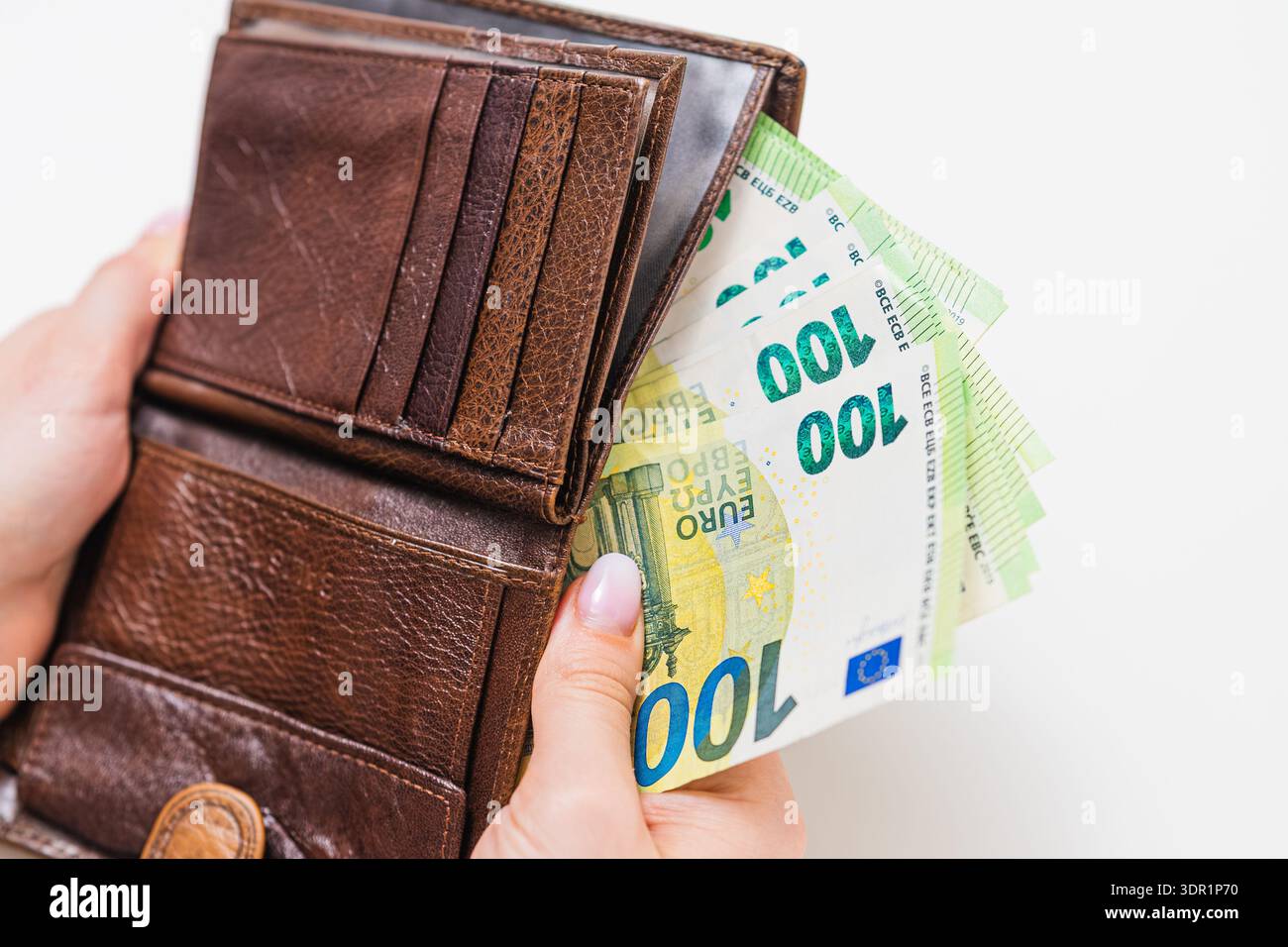 Donna che mette 100 banconote in euro in una borsa marrone a casa. Pianificazione finanziaria, reddito salariale, risparmi di cassa, gestione del denaro e concetto di bilancio familiare. Foto Stock
