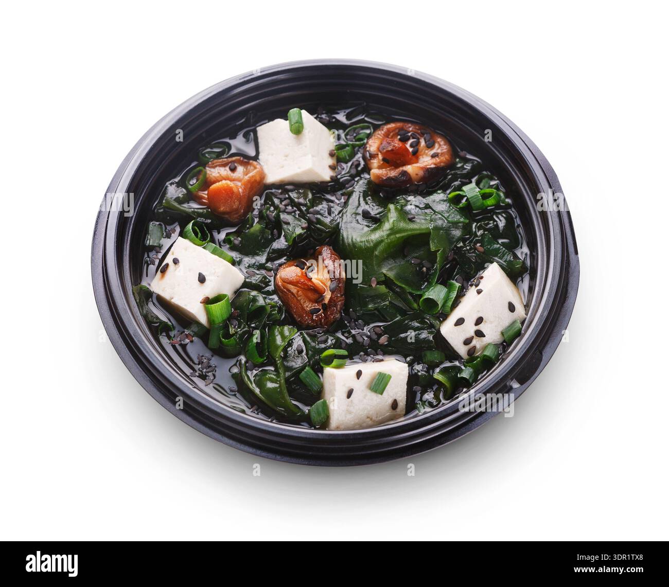 Zuppa di verdure con tofu e frutti di mare in una ciotola nera su sfondo bianco Foto Stock