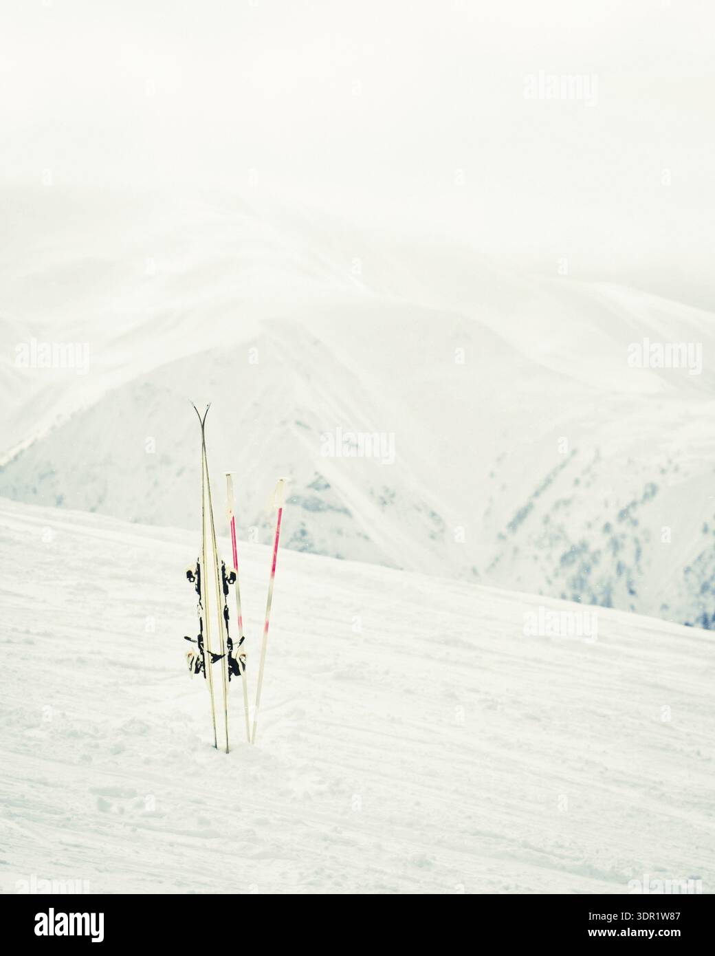 Coppia di sci bianchi con pali piantati nella neve su un pendio di montagna con vette alpine sullo sfondo, concetto di sport invernale, vacanza sugli sci, affitti, qualit Foto Stock