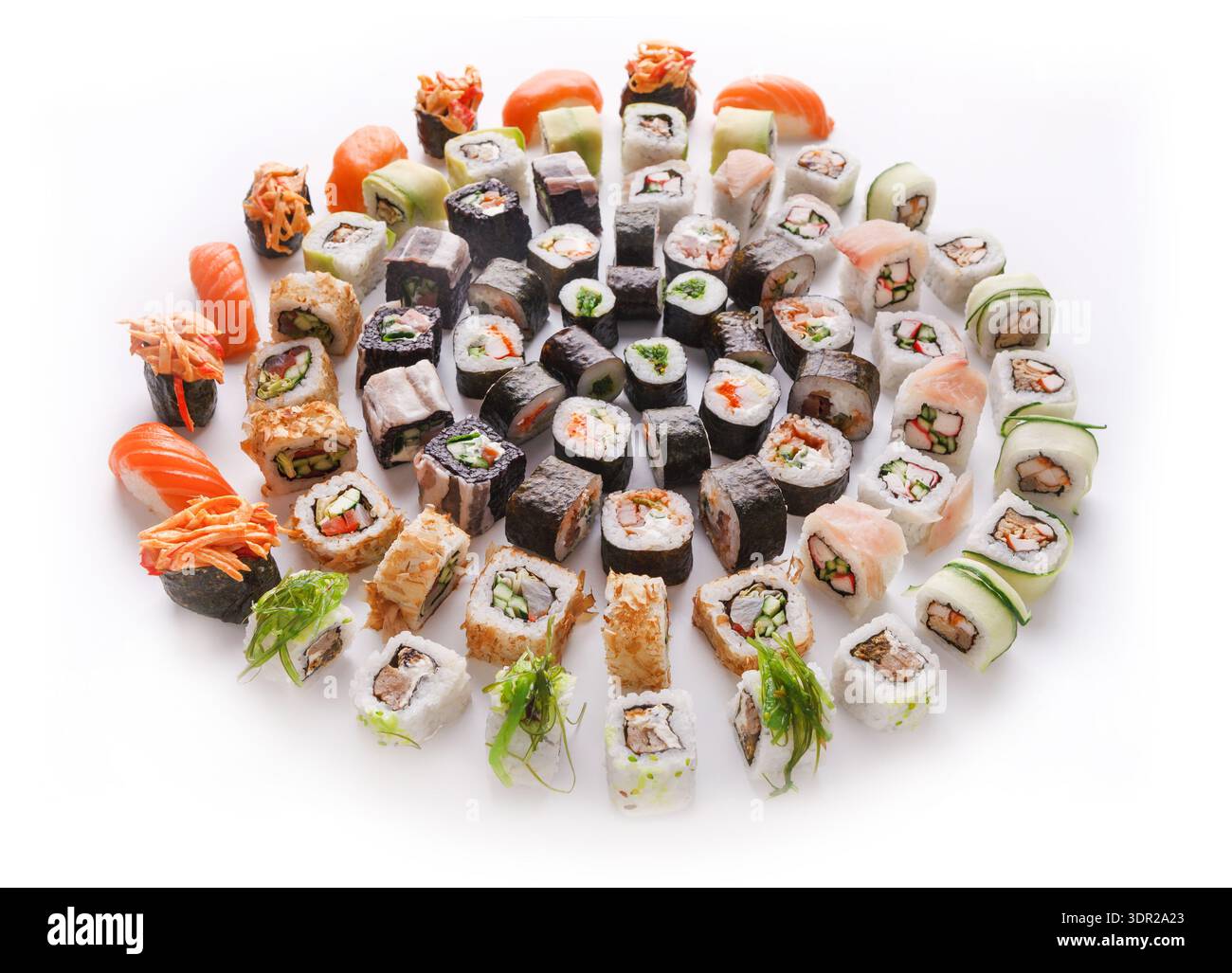 Diversi tipi di sushi disposti in un motivo circolare su una superficie bianca Foto Stock