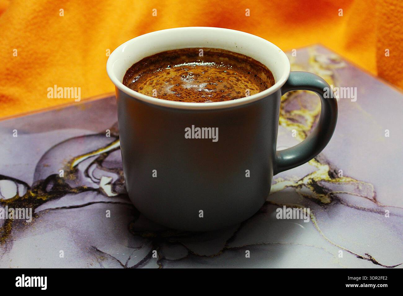 Primo piano di una tazza in ceramica grigia riempita di caffè nero caldo. Foto Stock