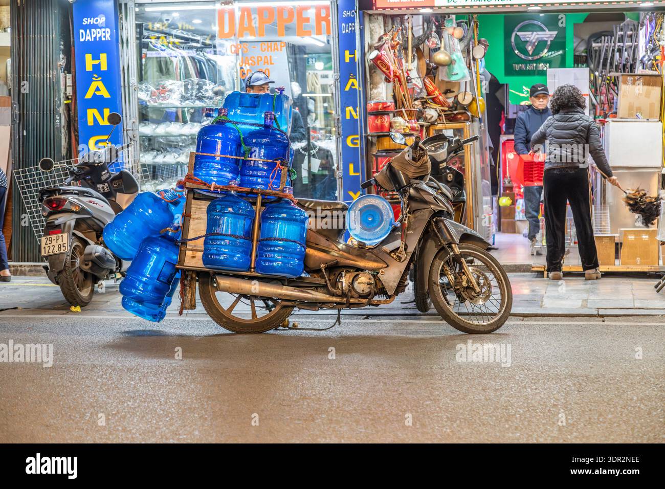 Grandi bottiglie d'acqua di plastica blu consegnate in moto ad Hanoi, Vietnam. Foto Stock
