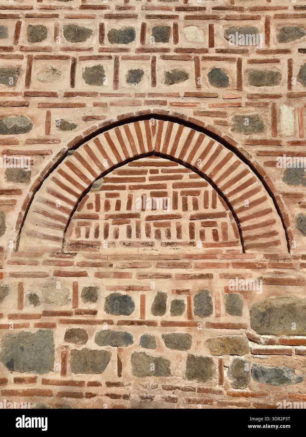 Frammento di muratura e archi della Moschea Dzhumaya a Plovdiv, Bulgaria. Architettura ottomana tradizionale che utilizza mattoni e pietra alternati. Foto Stock