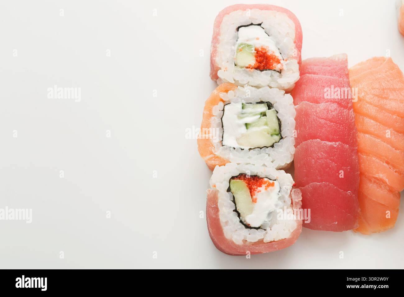 Sushi Rolls e pezzi di Sashimi su una superficie bianca pronti per essere gustati in un ristorante Foto Stock