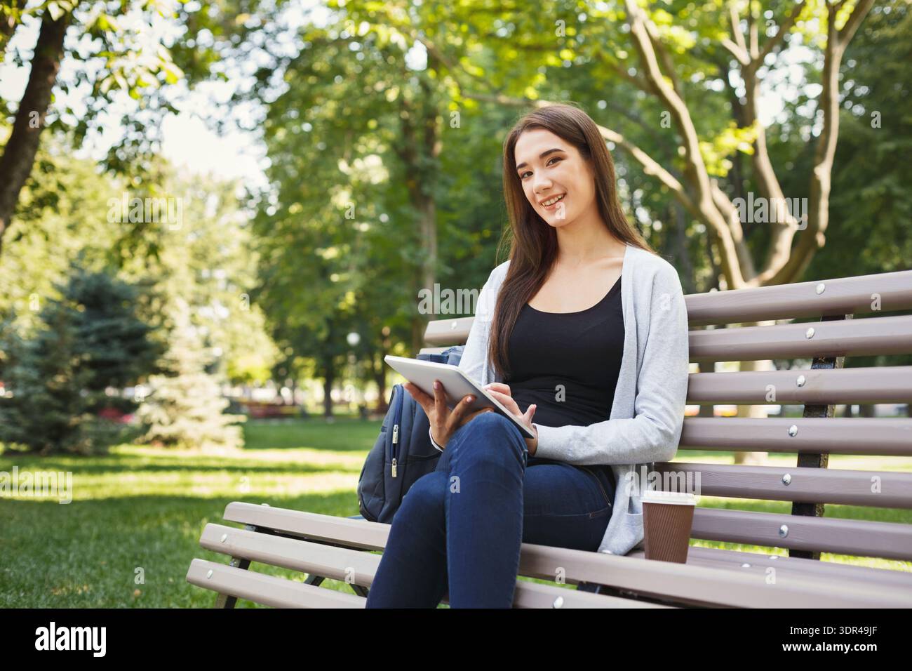 Giovani che si godono del tempo a Park con tablet e tazza di caffè in un giorno di sole Foto Stock