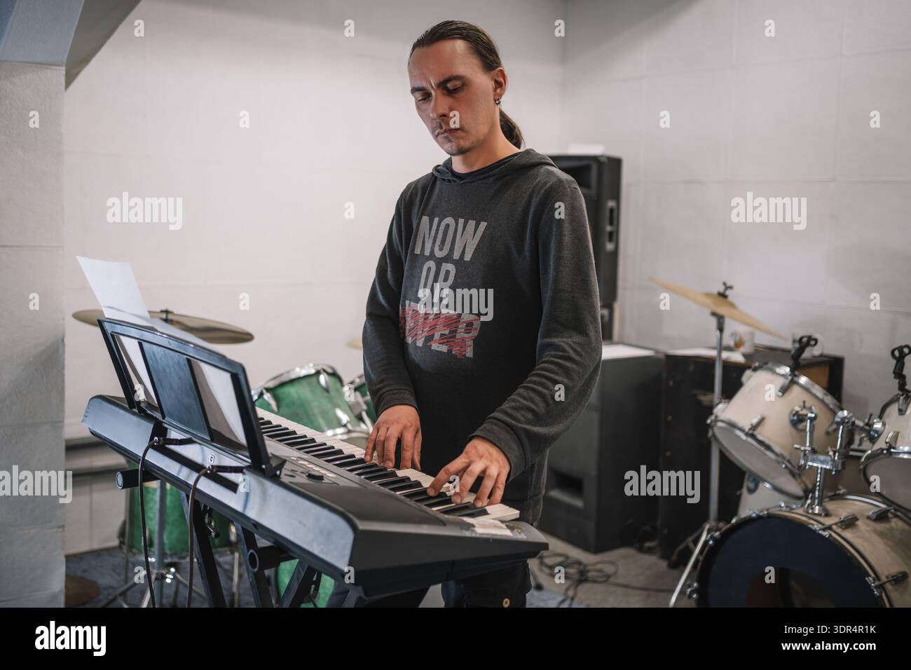 Musicista che suona sintetizzatore vicino a strumenti musicali in studio. il musicista sta provando in studio. Foto Stock