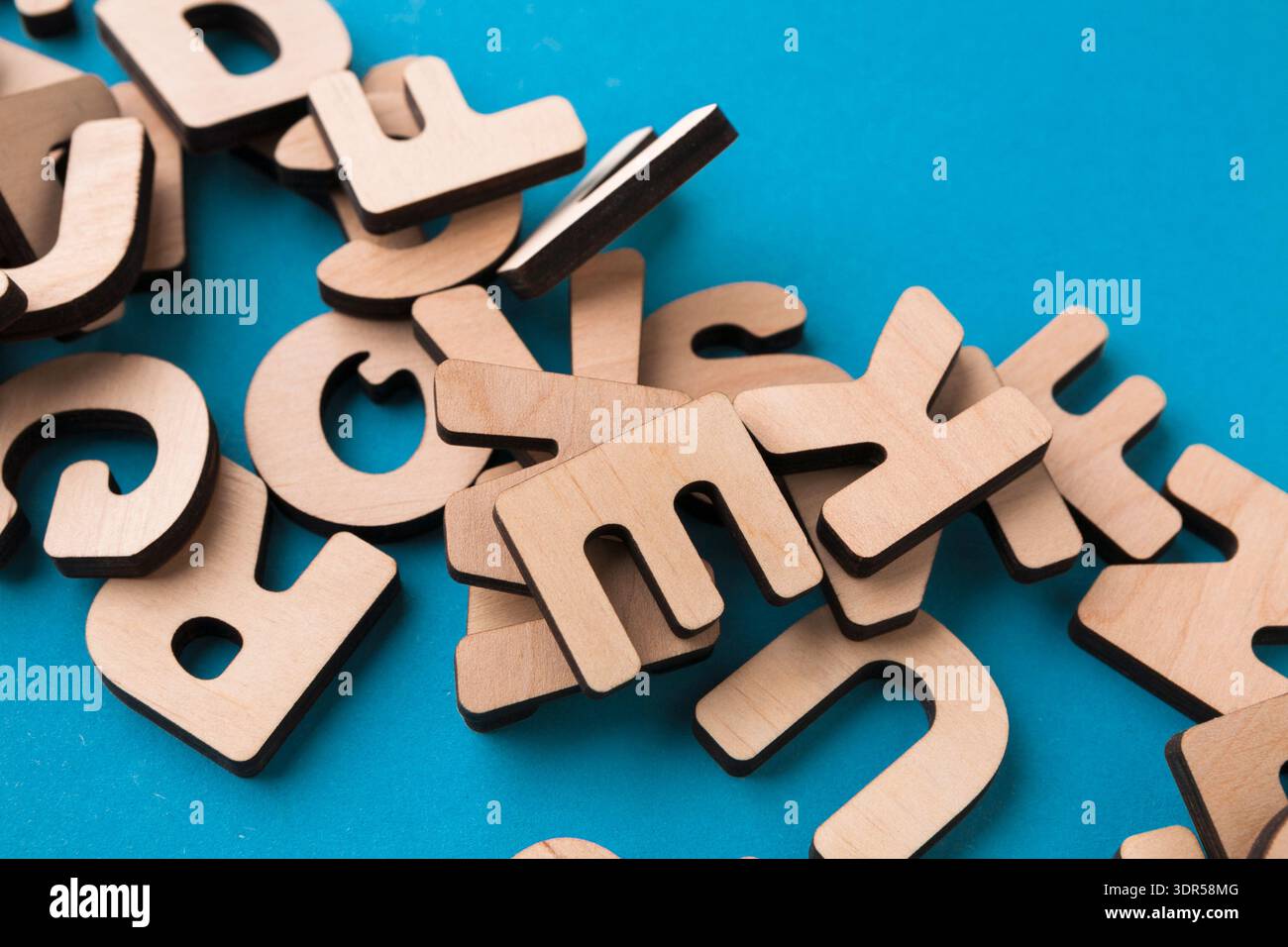 Le lettere di legno sono sparse su una superficie blu in un'attività didattica per bambini e adulti Foto Stock