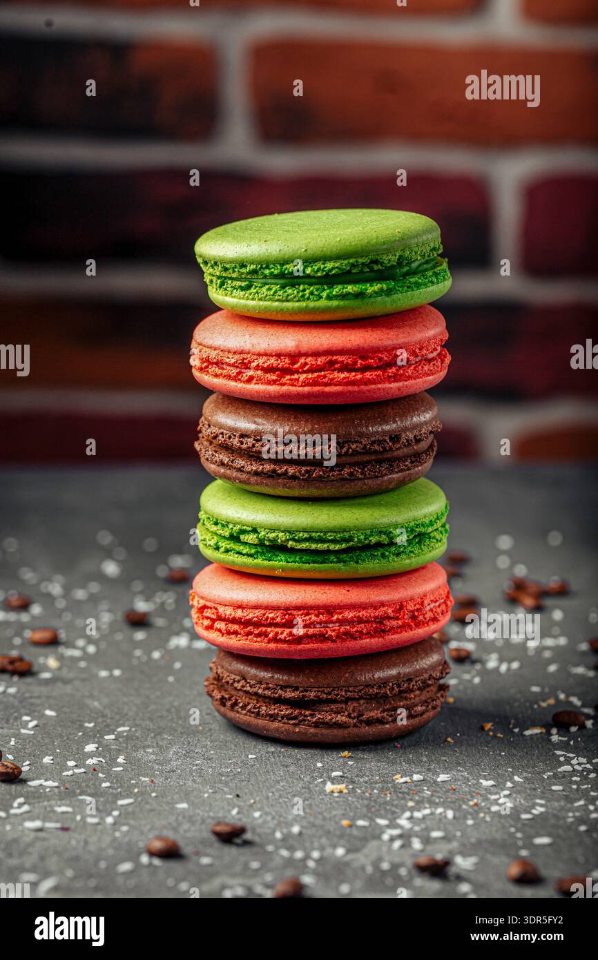 Macaron colorati si impilano sul tavolo scuro Foto Stock
