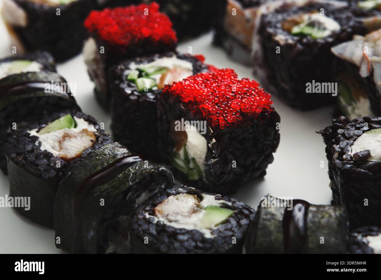 Sushi Rolls con vari condimenti serviti su un piatto bianco durante il pranzo Foto Stock