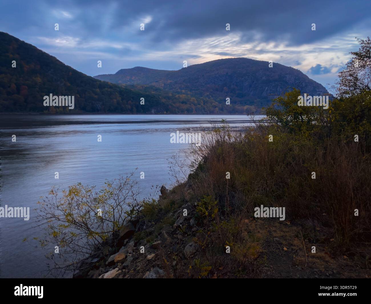 La tempesta serale d'autunno illumina il fiume Hudson con la Storm King Mountain nelle Hudson Highlands, New York. Foto Stock