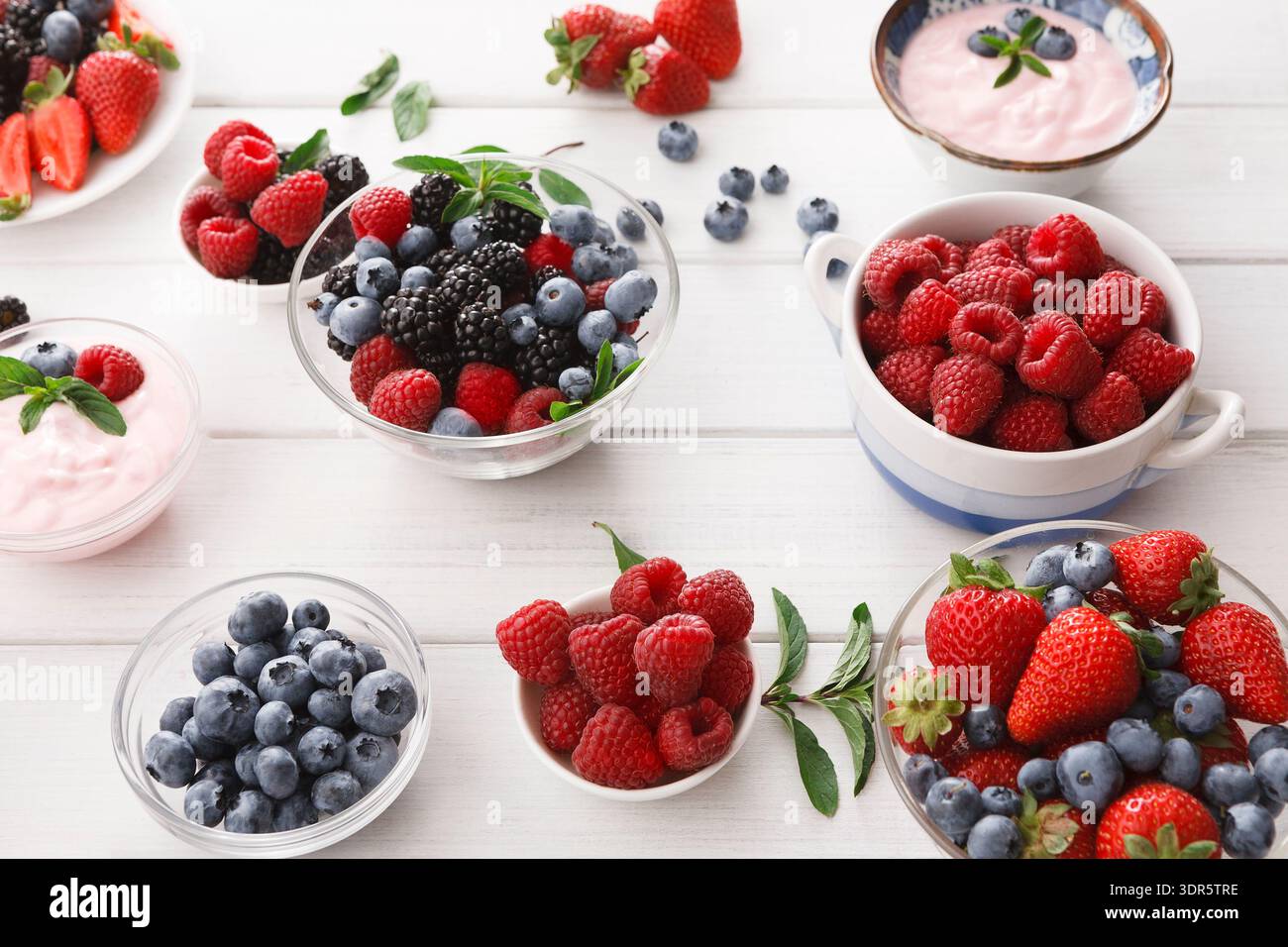 Bacche fresche in ciotole disposte su un tavolo per una vivace esposizione di frutta in una cucina Foto Stock