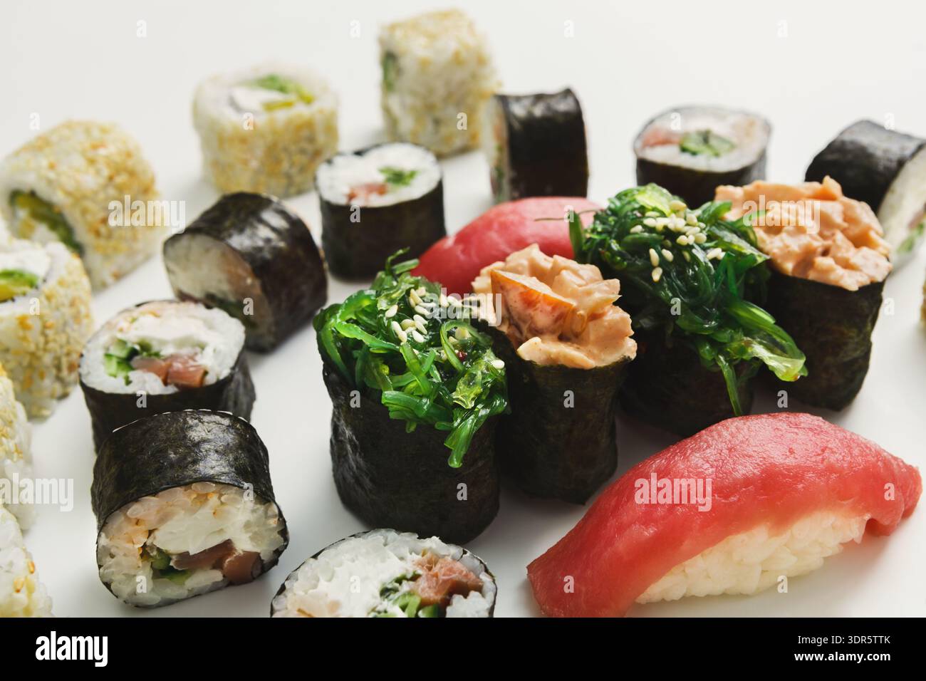 Varietà di sushi serviti su un piatto bianco con diversi ripieni di pesce e verdure Foto Stock