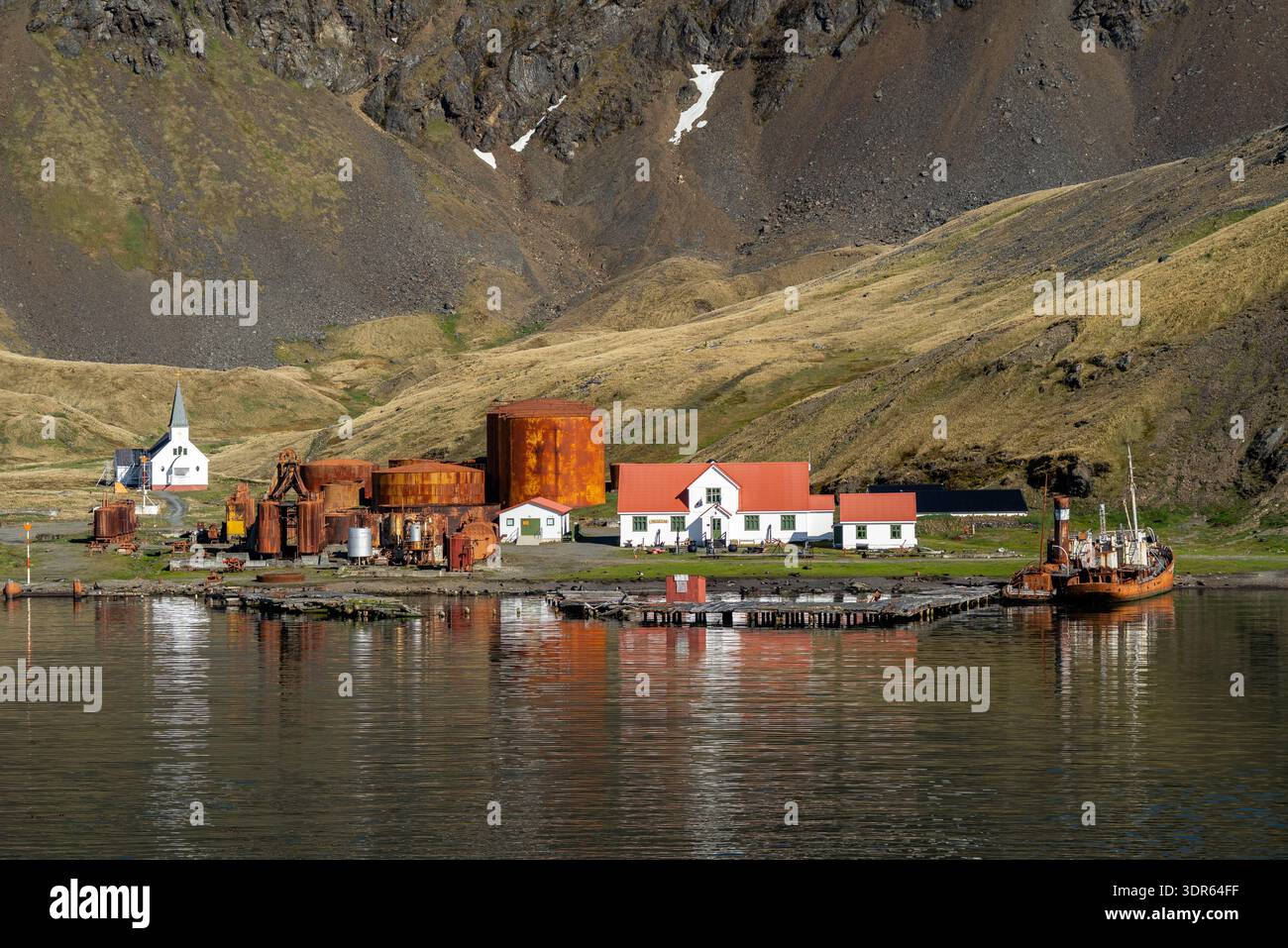 Ammira la terra di una stazione baleniera abbandonata, chiesa, museo e ufficio postale con uno sfondo di montagna in estate, Grytviken, Georgia del Sud Foto Stock