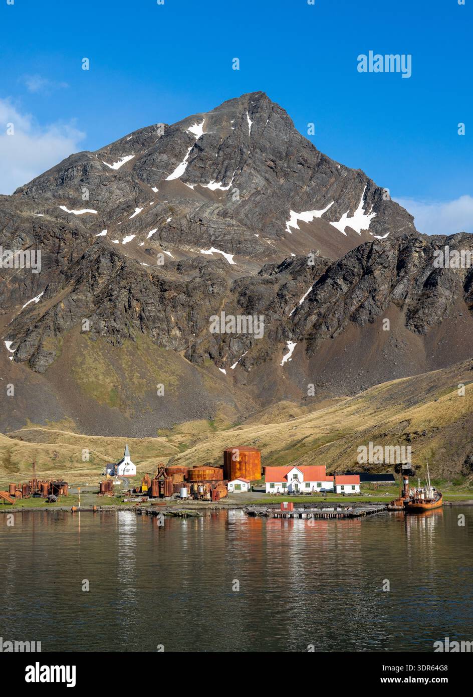 Ammira la terra di una stazione baleniera abbandonata, chiesa, museo e ufficio postale con uno sfondo di montagna in estate, Grytviken, Georgia del Sud Foto Stock