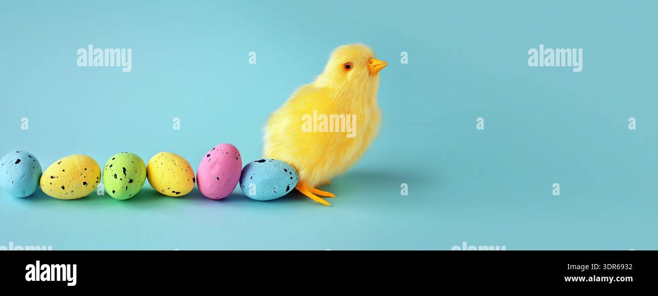 Decorazione pasquale di un pulcino giallo con una fila di uova di Pasqua colorate Foto Stock