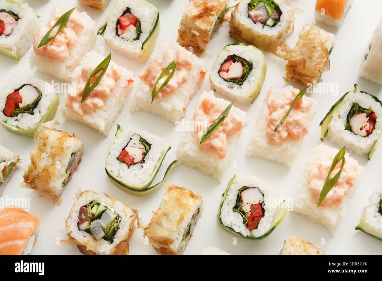 Diversi tipi di sushi disposti ordinatamente su una superficie piana durante l'ora del pasto Foto Stock