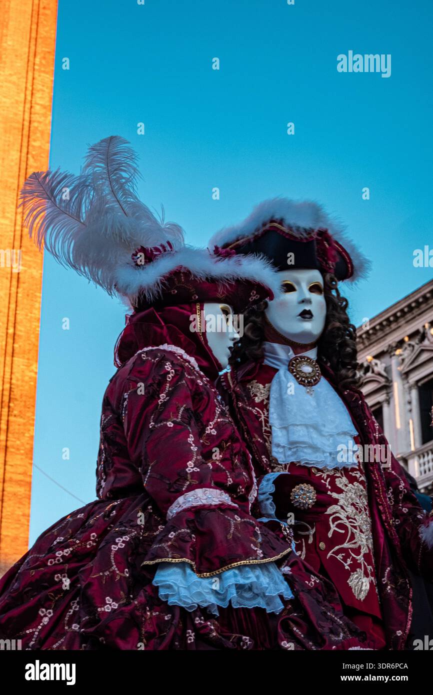 Venezia, Italia - 15 febbraio 2026: Un partecipante indossa un costume rosso ornato e pose una maschera tradizionale durante l'annuale Carnevale di Venezia Foto Stock