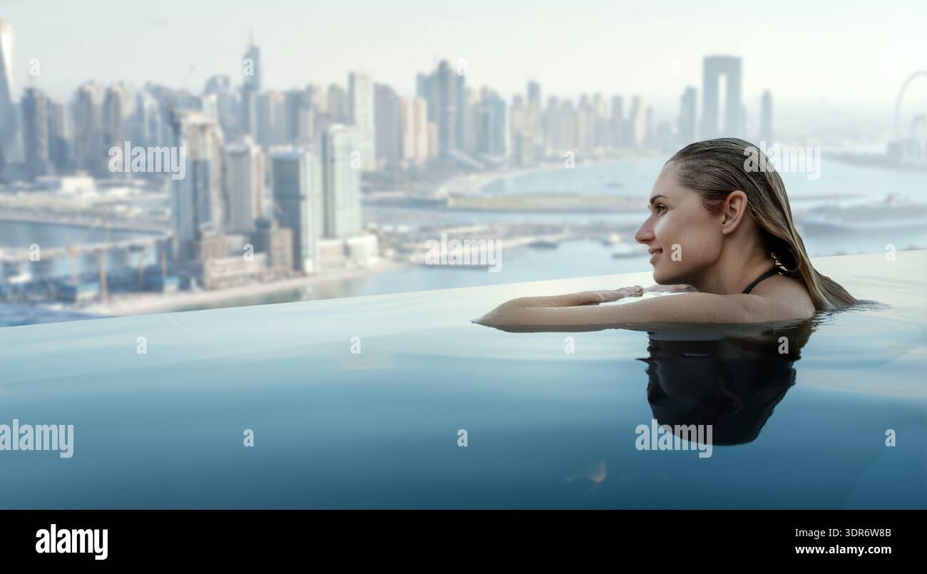 Donna che gode del panorama di Dubai dalla piscina a sfioro sul tetto. copia spazio Foto Stock