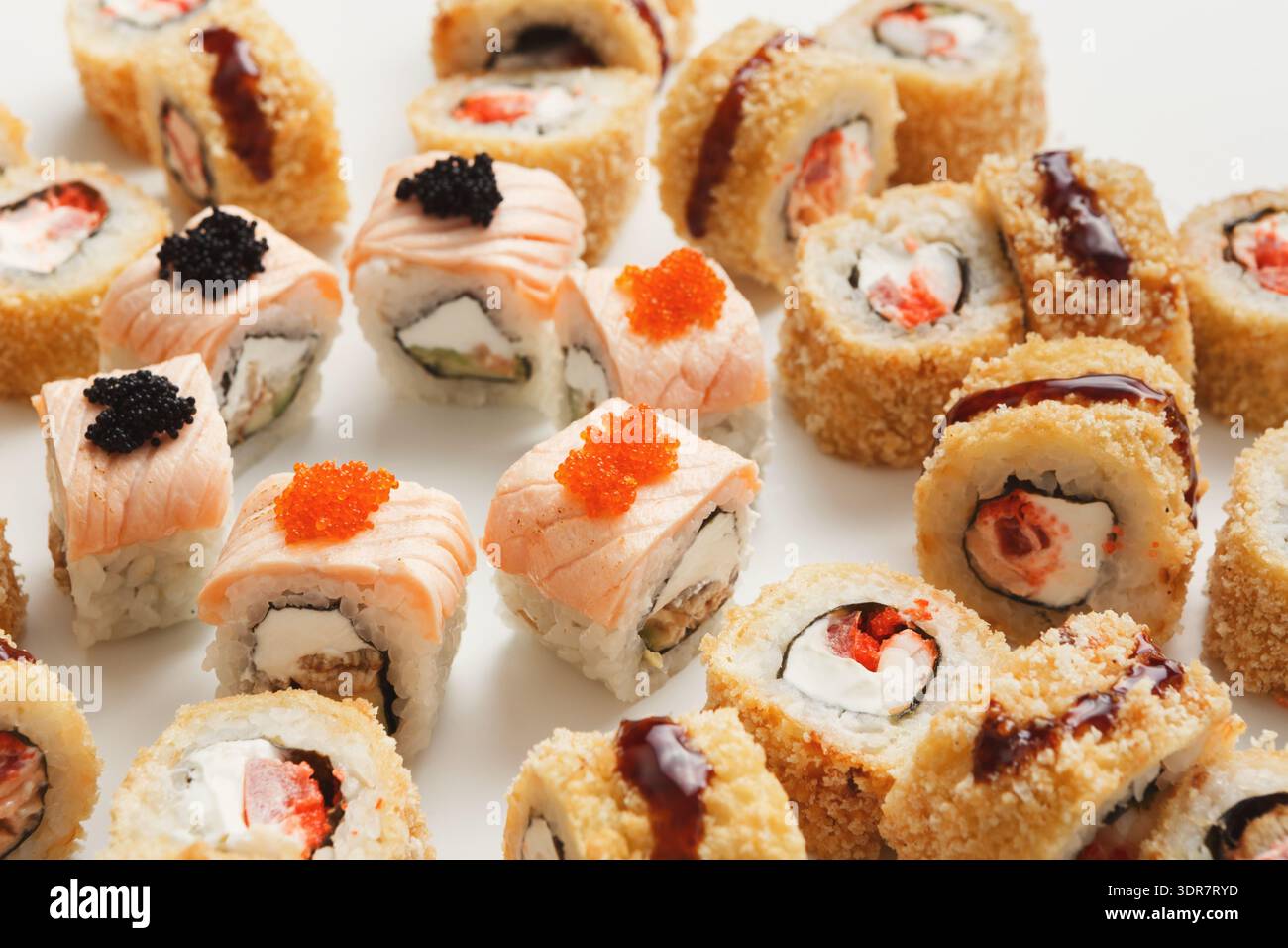 Piatto di sushi con vari panini con frutti di mare e condimenti esposti su un semplice sfondo Foto Stock
