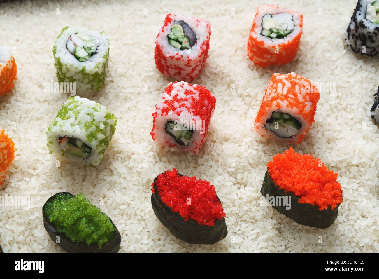 Colorati Sushi Rolls collocati su un letto di riso in un ristorante di sushi durante l'ora di pranzo Foto Stock
