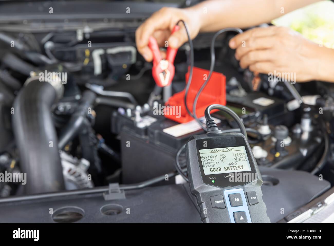 Man sta misurando la potenza della batteria AGM di un'auto suv tramite un tester per batterie a casa. Foto Stock