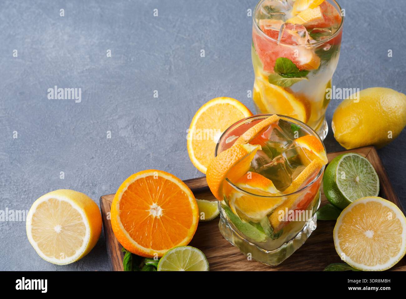 Bevanda rinfrescante con agrumi ed erbe aromatiche su un tavolo grigio Foto Stock