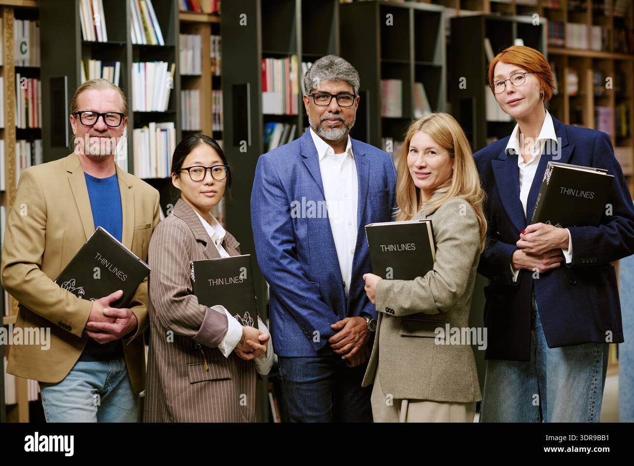Gruppo diversificato di uomini e donne che tiene libri in posa con autore alla presentazione Foto Stock