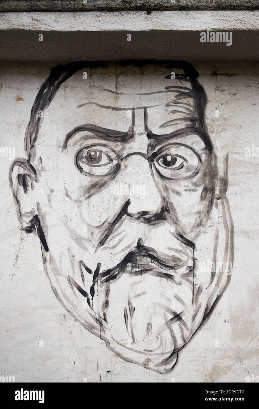 Grande Street art dipinta a mano in bianco e nero di un anziano barbuto con occhiali rotondi e un pizzetto dipinto direttamente su una pietra bianca W Foto Stock