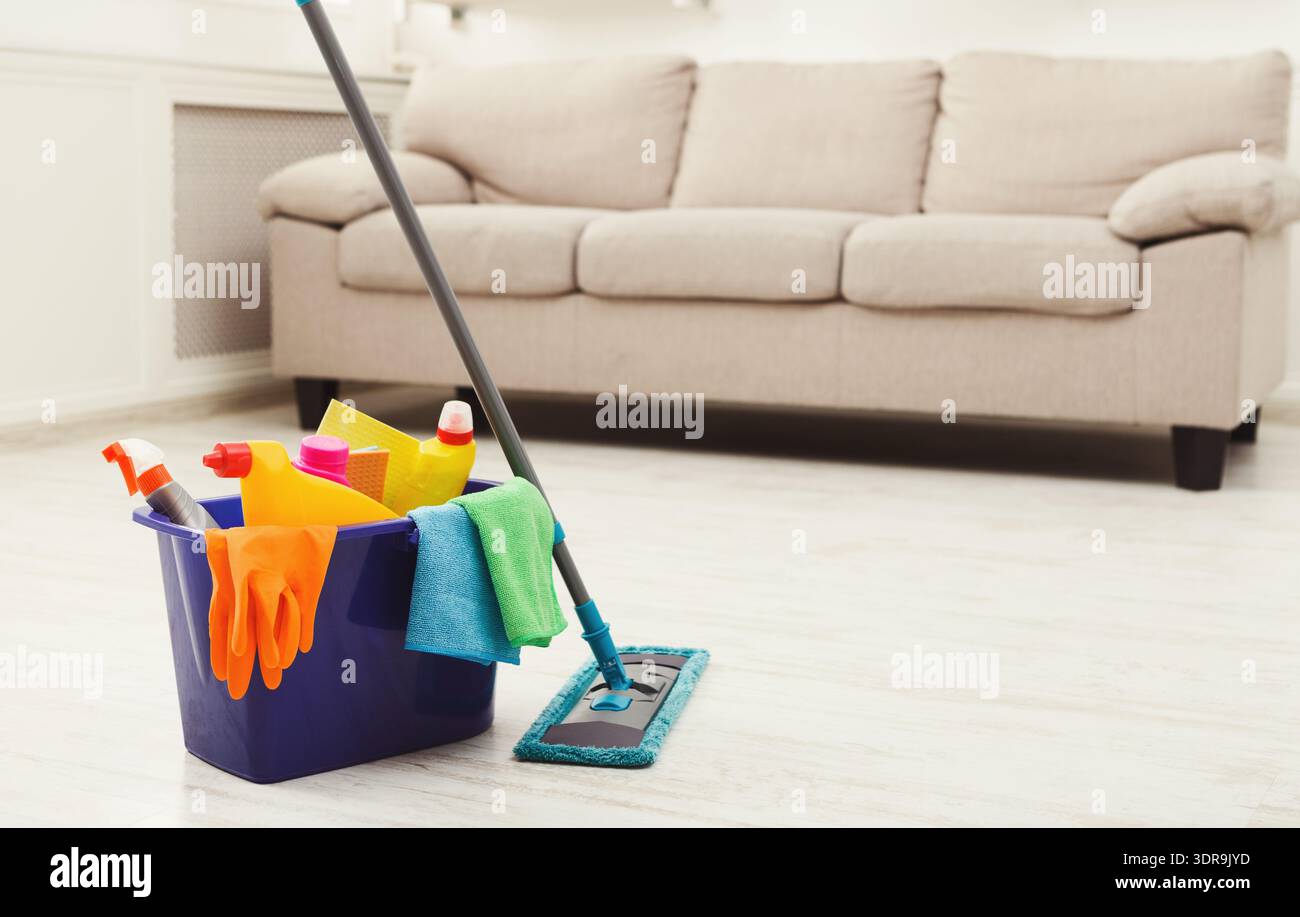 Materiali di consumo per la pulizia disposti in un secchio vicino a un lettino in un soggiorno Foto Stock