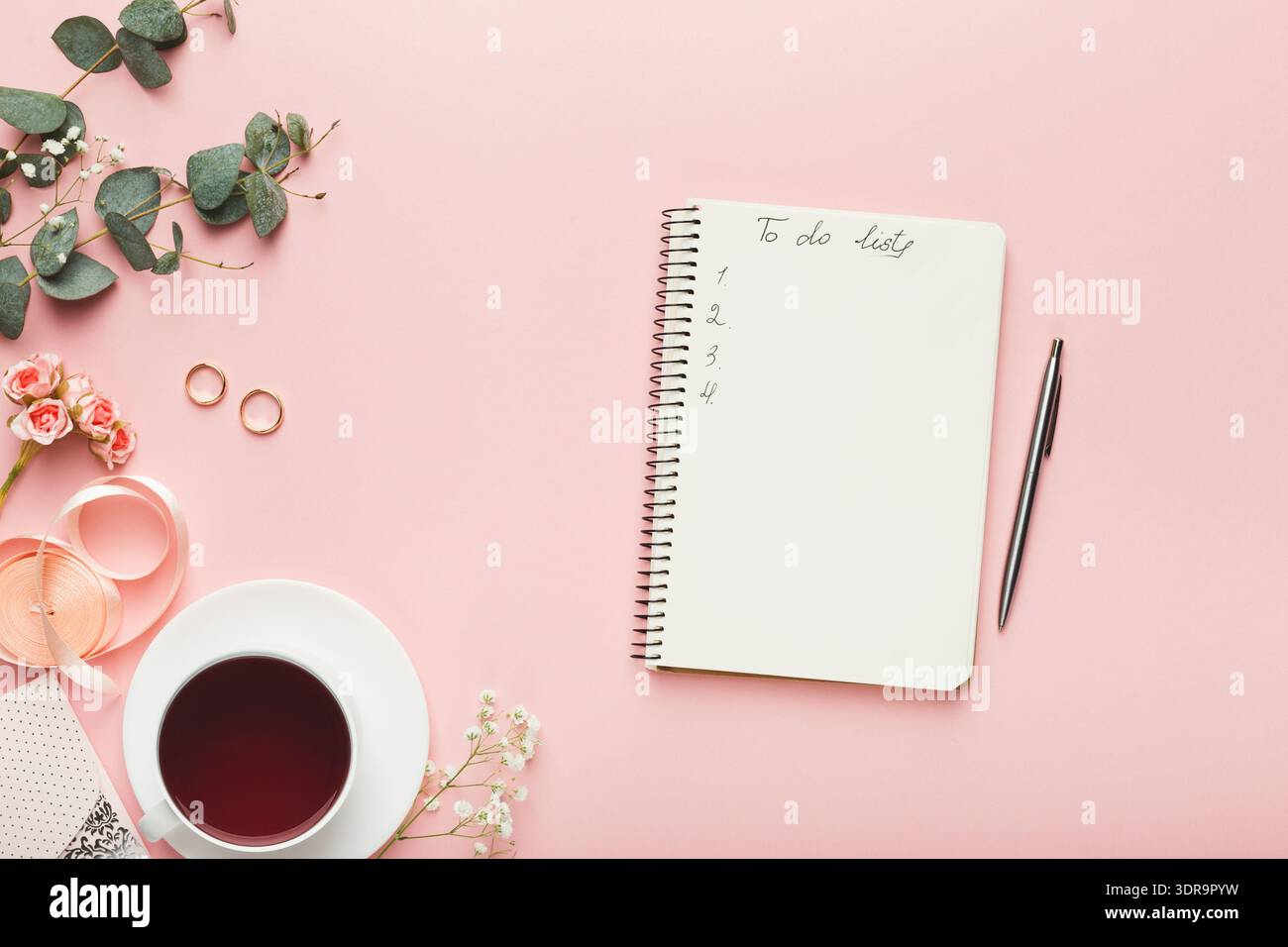 Collezione di articoli di uso quotidiano disposti su una superficie rosa chiaro per un momento produttivo Foto Stock