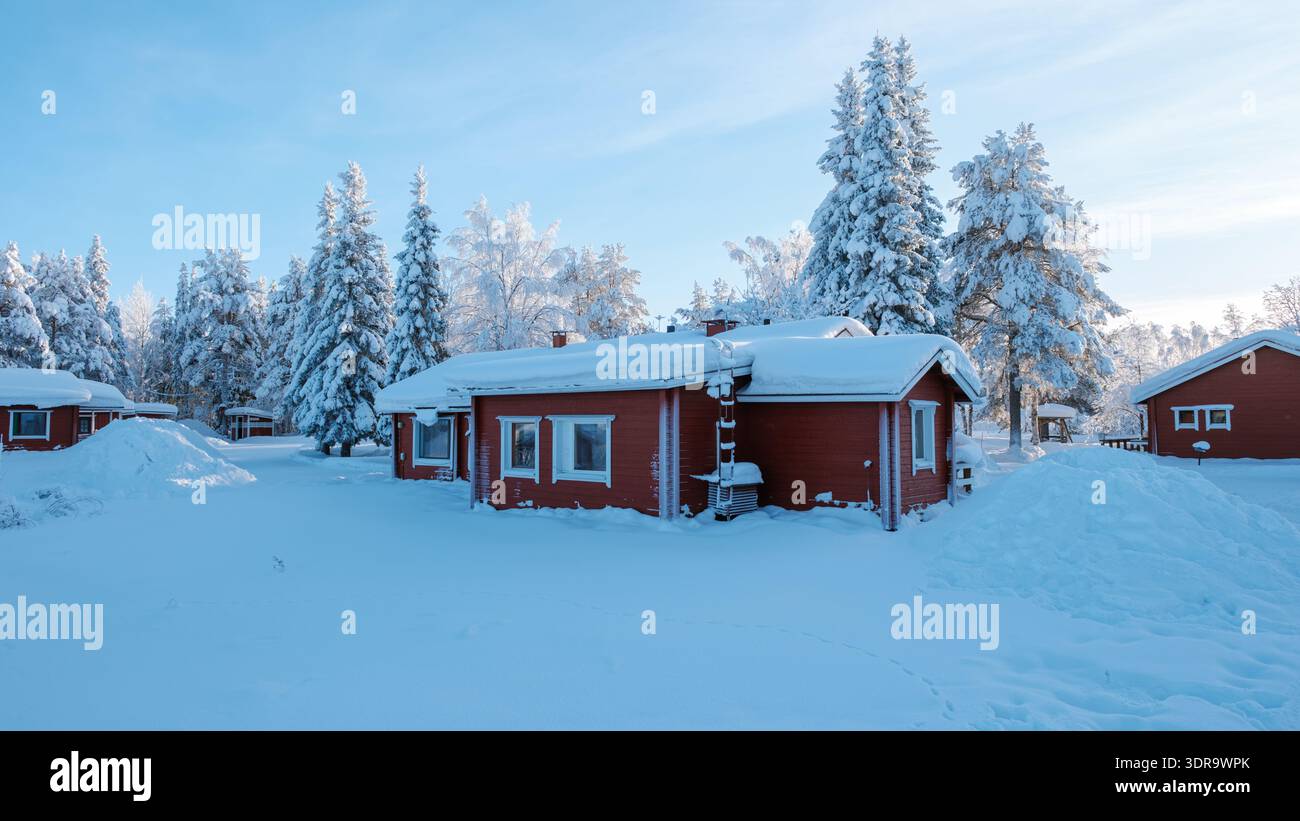 Scoprite il fascino del villaggio di Akaslompo in Lapponia, Finlandia, con i suoi invitanti cottage rossi circondati da neve bianca incontaminata. Foto Stock