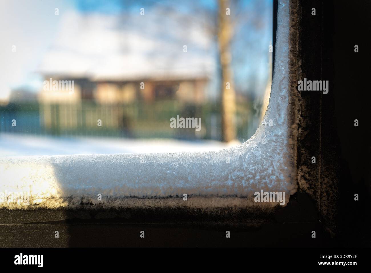 Gelo all'interno di una finestra in inverno, mostrando una casa ghiacciata con delicati cristalli di ghiaccio che coprono il vetro. Bella ma preoccupante patt naturale Foto Stock