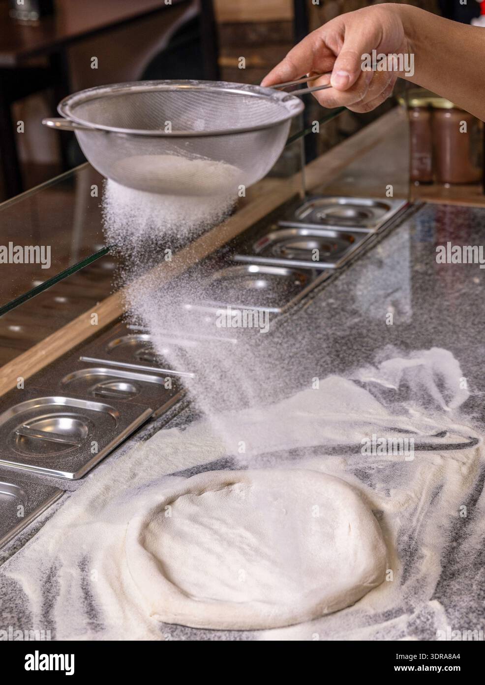 Lo chef professionista in cucina prepara l'impasto dalla farina per cucinare la pasta italiana e la pizza. Mani per sfregare la farina. Processo di preparazione della pizza Foto Stock