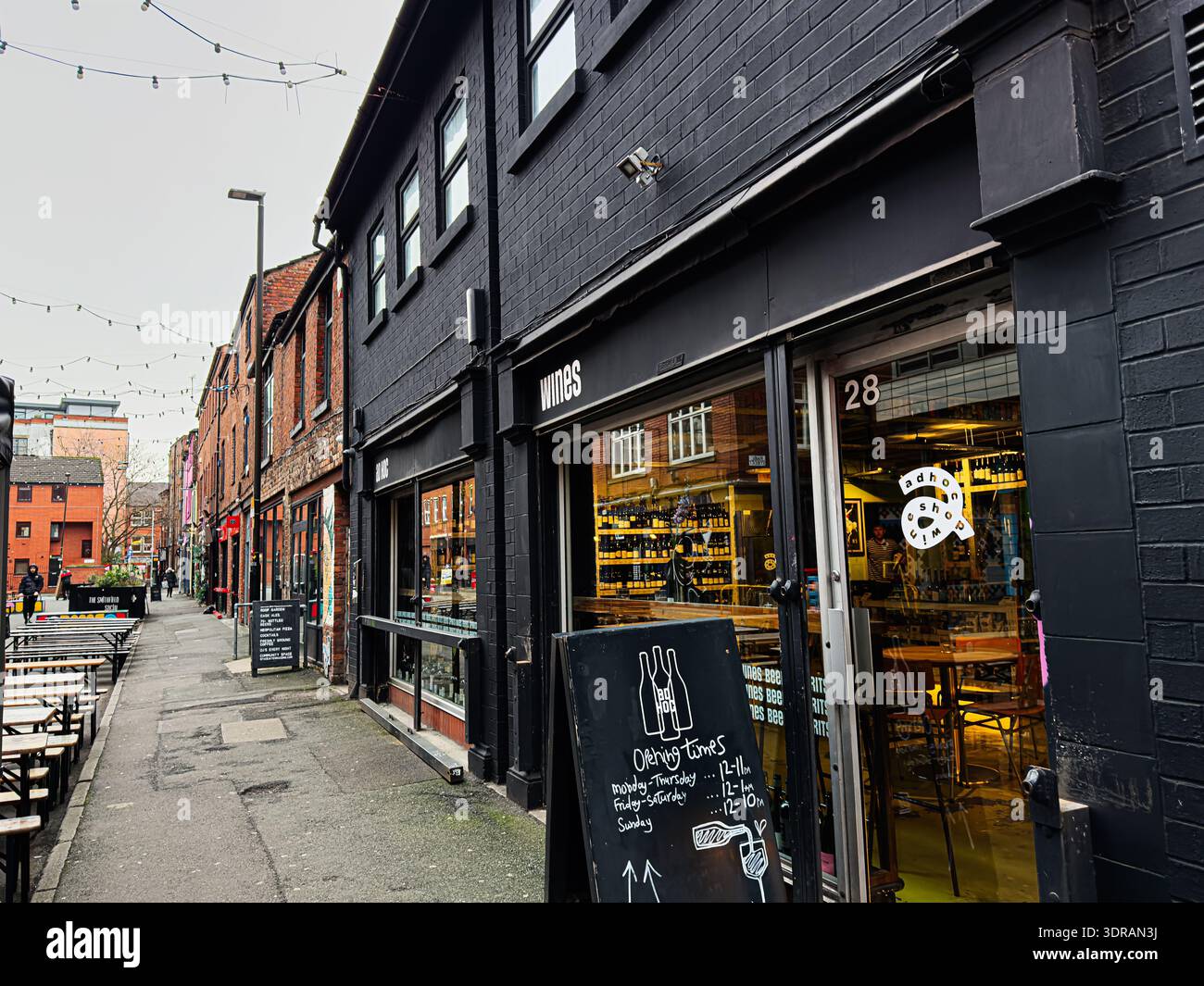 Manchester, Regno Unito - 26 gennaio 2026: Un negozio di mattoni a Manchester mostra l'enoteca ad hoc con interni luminosi e posti a sedere sul marciapiede. Foto Stock