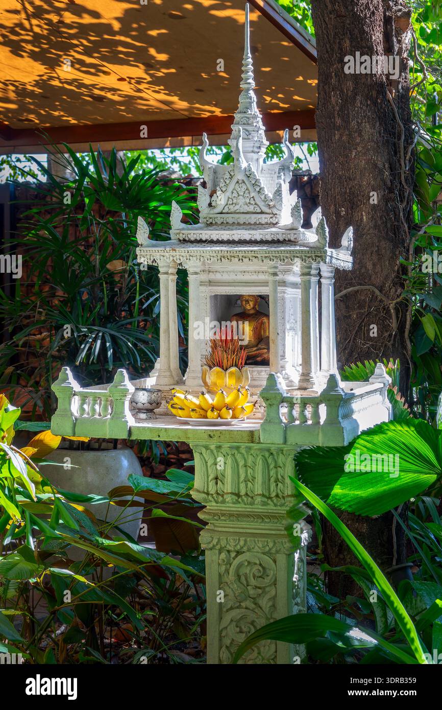 Casa tradizionale bianca dello Spirito, piccolo santuario con frutta, incenso e una statua dorata del Buddha in Cambogia, nel sud-est asiatico Foto Stock