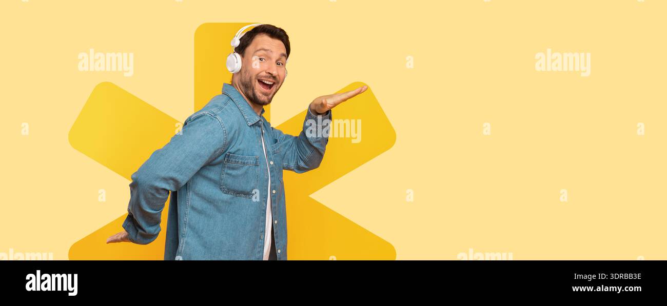 L'uomo che indossa le cuffie sorride mentre posa su uno sfondo giallo Foto Stock