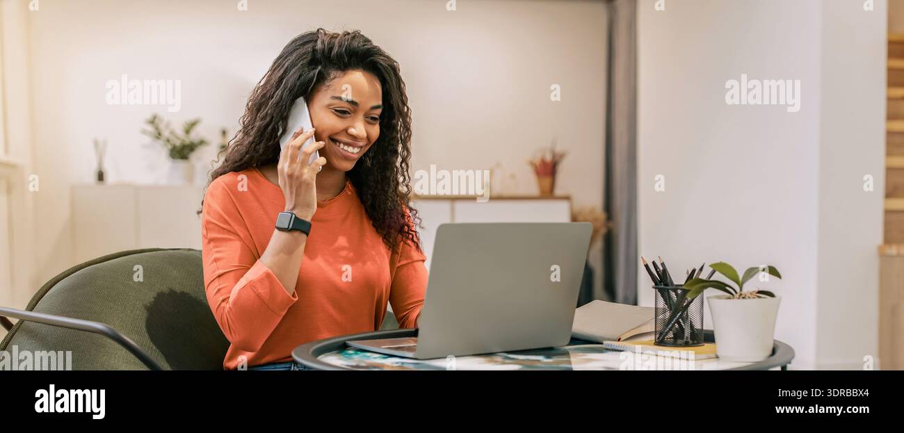 La donna parla al telefono mentre lavora su un notebook in ufficio domestico Foto Stock