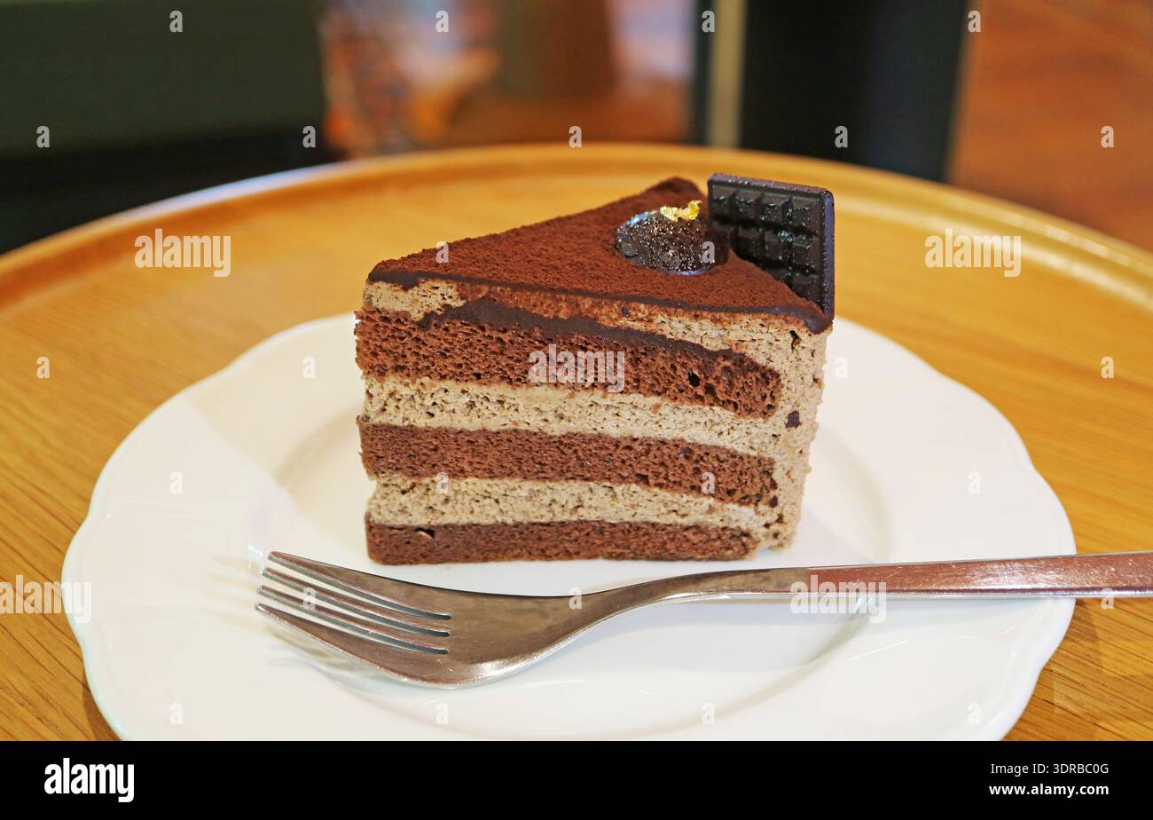 Una fetta di deliziosa e ricca torta al chiffon al cioccolato servita su un tavolo di legno Foto Stock