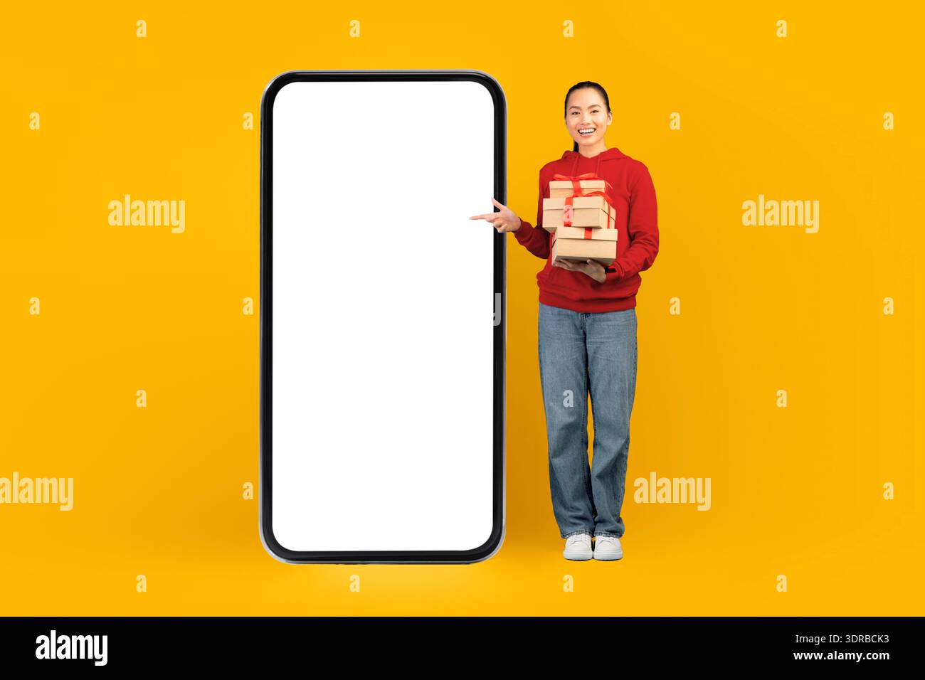La persona tiene pacchetti e punti su un'ampia schermata del telefono vuota su uno sfondo giallo brillante Foto Stock