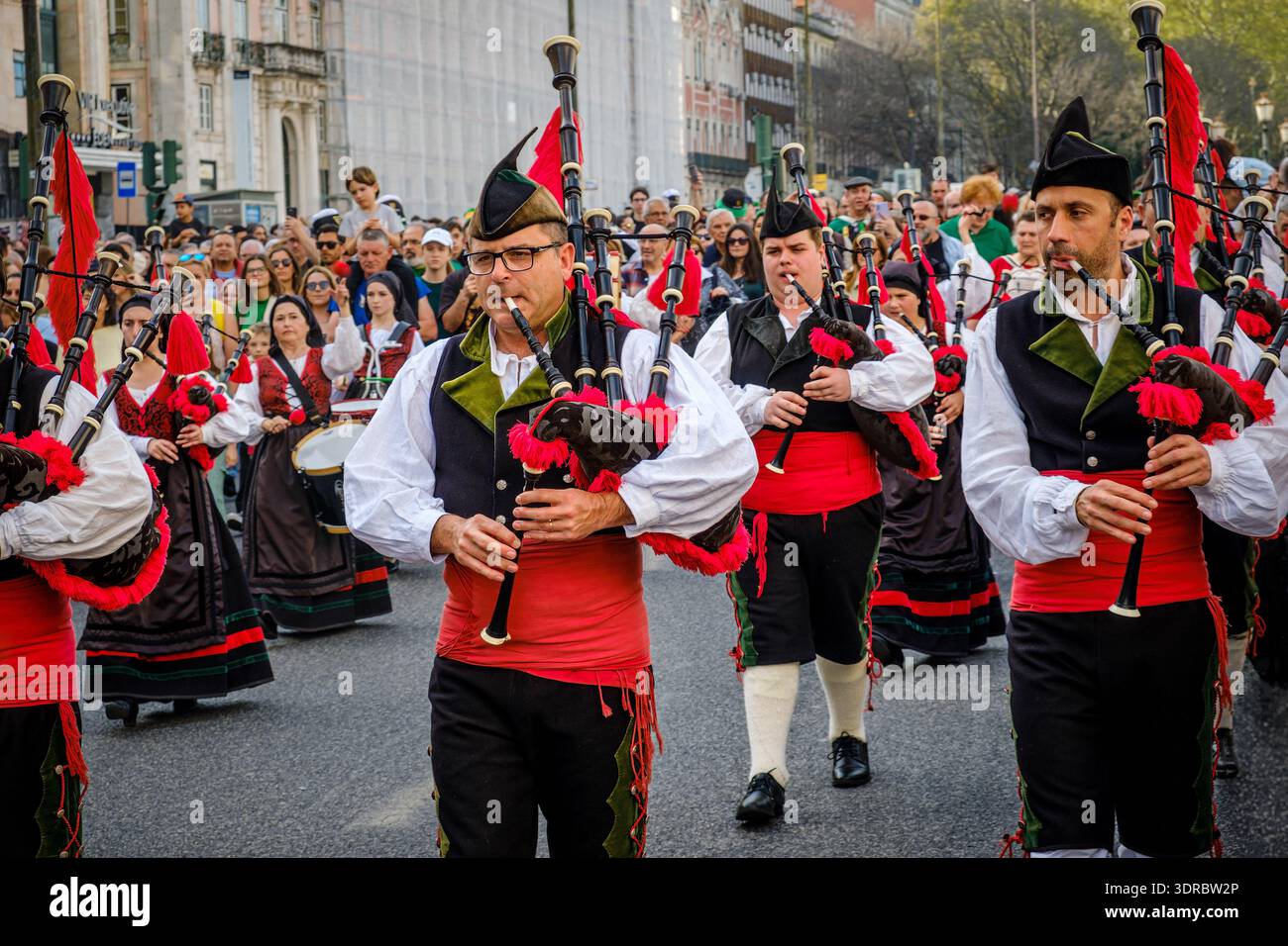 17 marzo 2024 - Lisbona, Portogallo: Banda di bagpiper che suona gaita iberica in costumi popolari tradizionali, gilet neri e fasce rosse, noti come gaiteiros in processione in sfilata il giorno di San Patrizio, evento culturale, esibizione musicale, celebrazione del patrimonio celtico Foto Stock