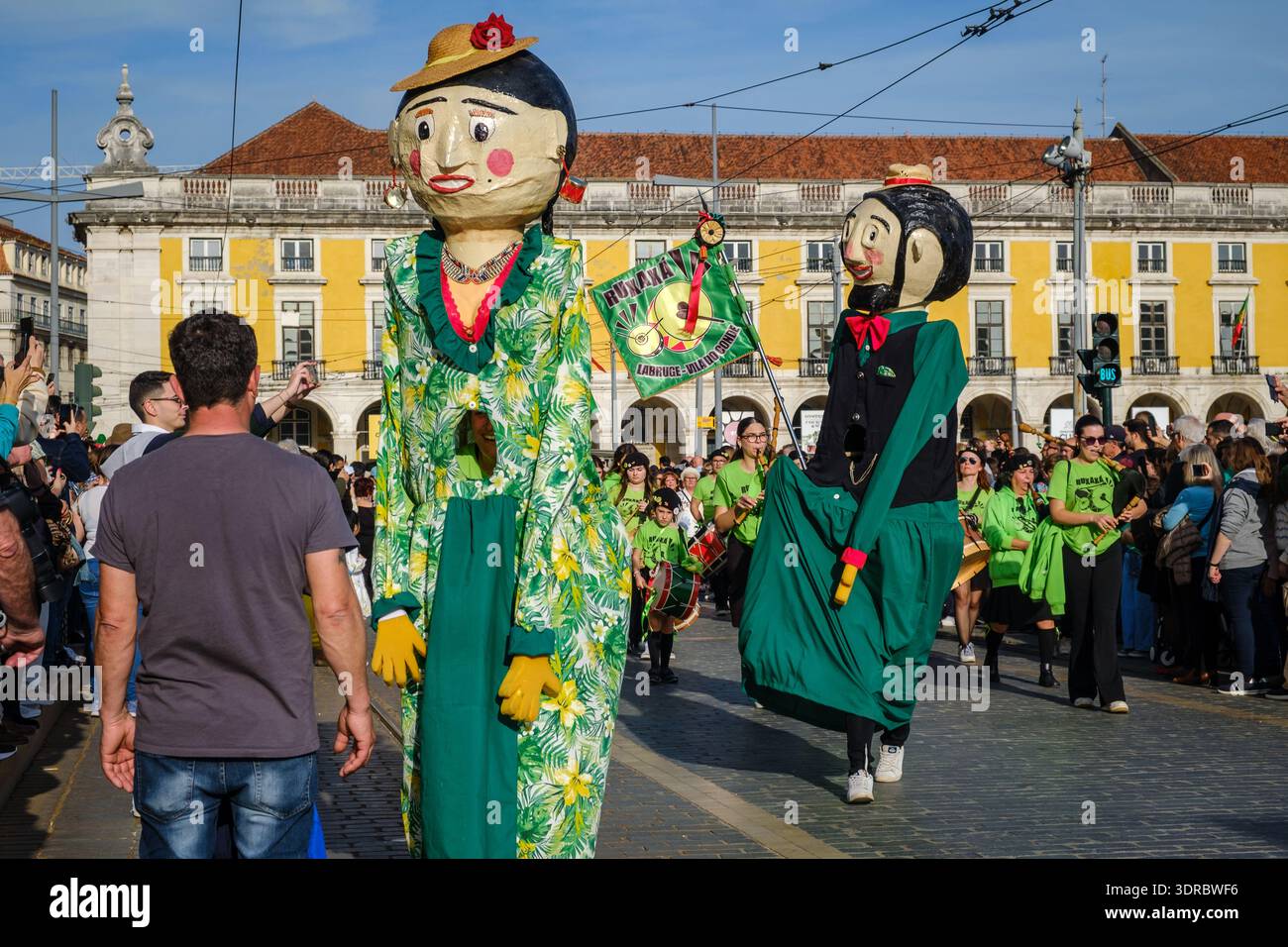 17 marzo 2024 - Lisbona, Portogallo: Grandi marionette giganti tradizionali conosciute come gigantoni in coloratissimi costumi verdi a Praca do commercio o Commerce Square durante la sfilata del giorno di San Patrizio nella giornata di sole. Sfondo festivo della folla, celebrazione del patrimonio culturale Foto Stock