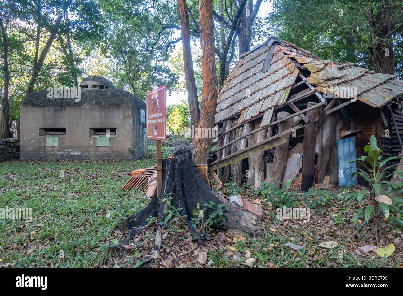 Sito storico caratterizzato da un bunker abbandonato in cemento armato accanto a una capanna in legno in rovina, Museo della Guerra di Penang, Malesia Foto Stock