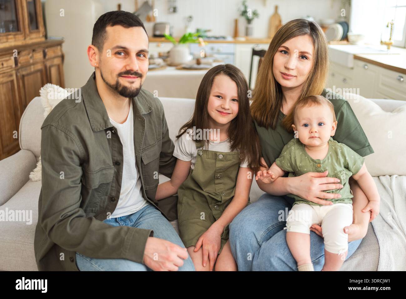 Famiglia felice a casa. Madre, padre, due figli, figlie che si rilassano sul divano al coperto. Mamma, papà, genitori, bambine, bambini, relax e gioco Foto Stock